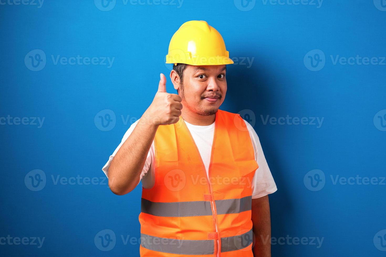 dikke aziatische bouwvakker met oranje veiligheidsvest en helm met duim omhoog foto