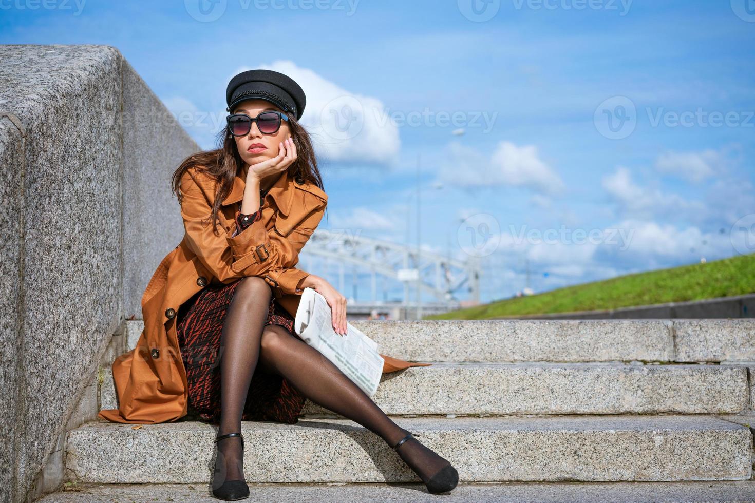 jonge vrouw zit op de trappen aan de kade met een krant in de hand foto