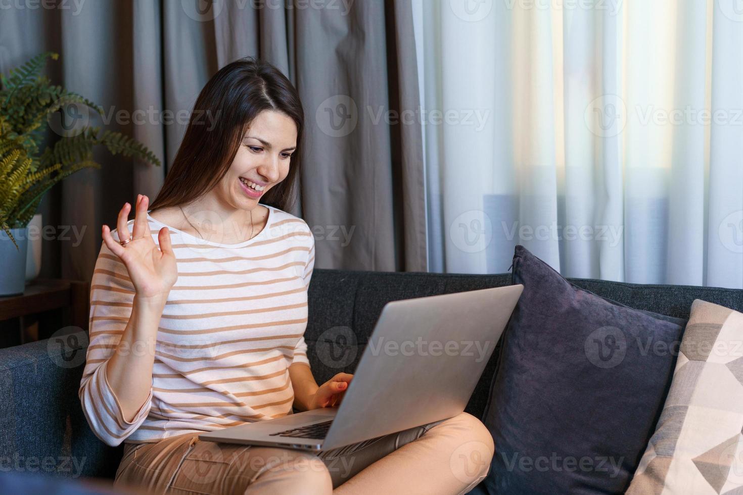 vrolijke jonge vrouw ontspannen thuis na het werk, praten met een vriend of foto