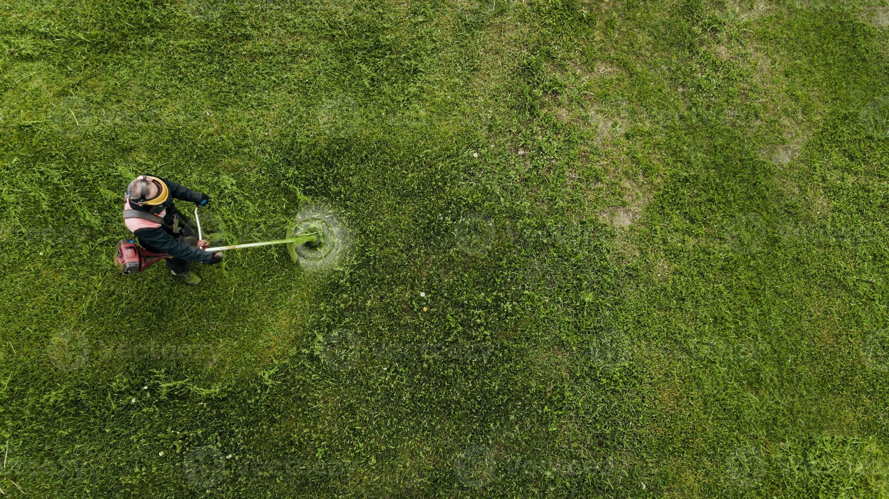 bovenaanzicht man werknemer gras maaien met grasmaaier. foto