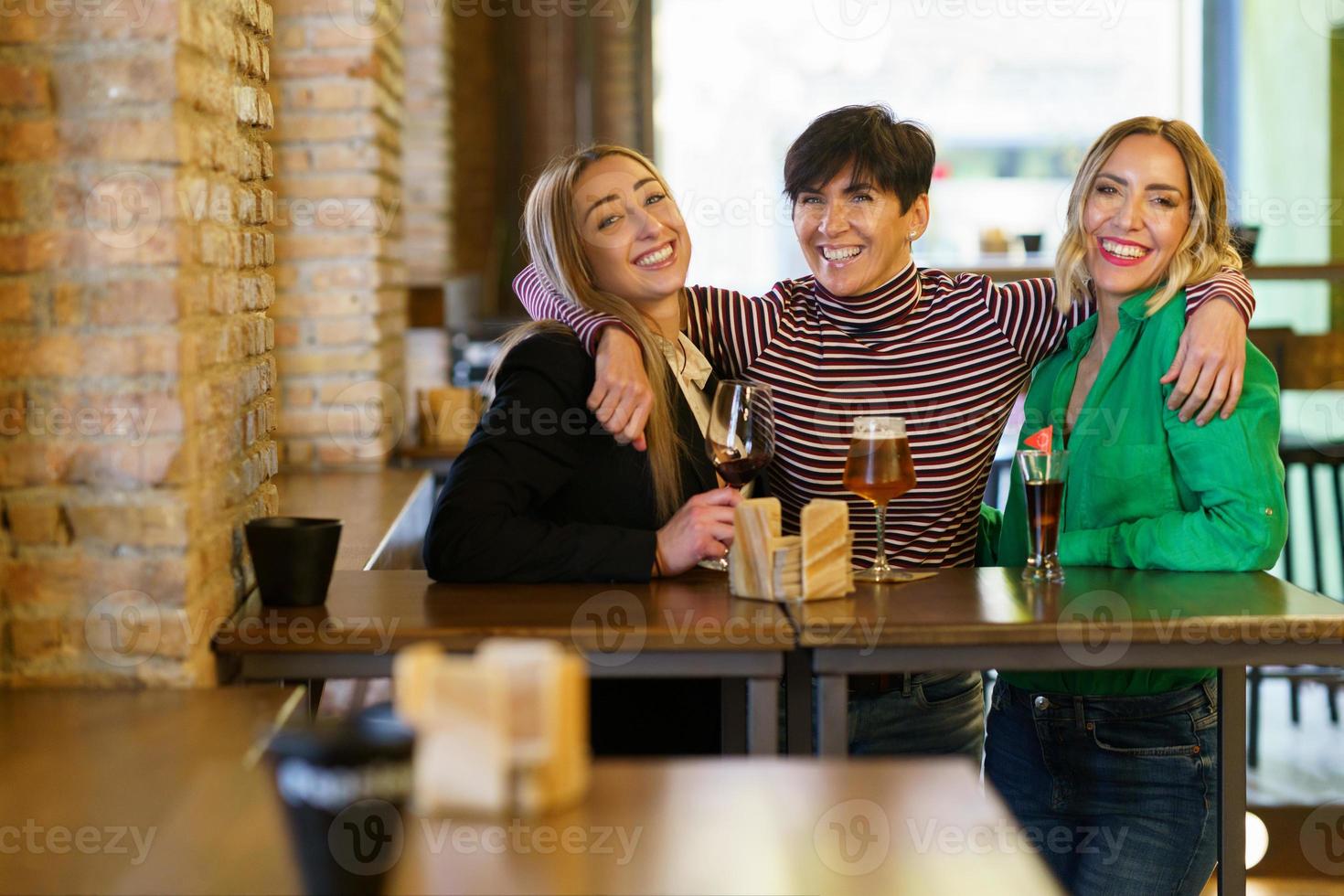 vrolijke vriendinnen knuffelen tijdens feest in bar foto