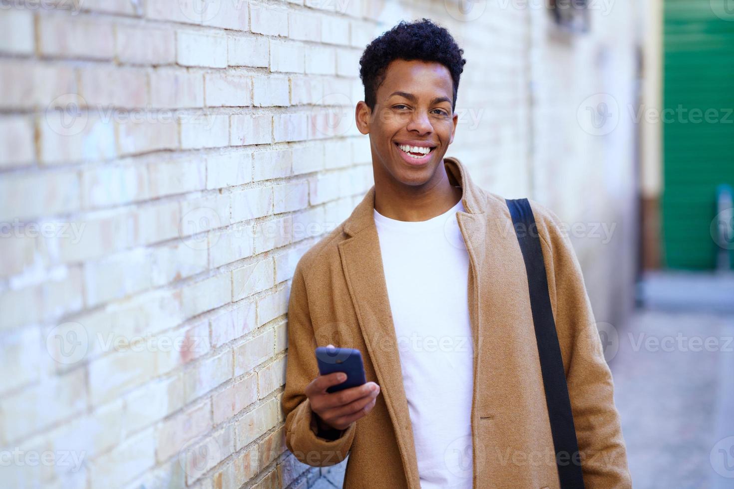 jonge zwarte man met zijn smartphone buitenshuis. foto