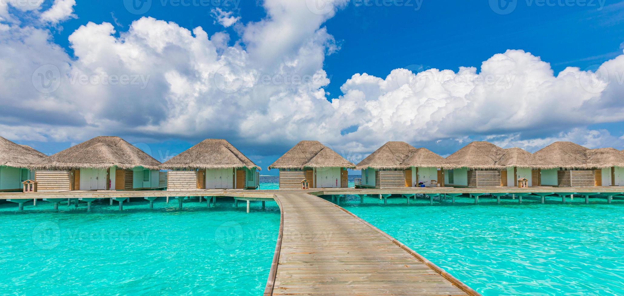overwater bungalows in de indische oceaan, maldiven eilanden. tropische oceaanlagune, turkoois water, idyllische bewolkte hemel. zomervakantie, vakantie, reisbestemming foto