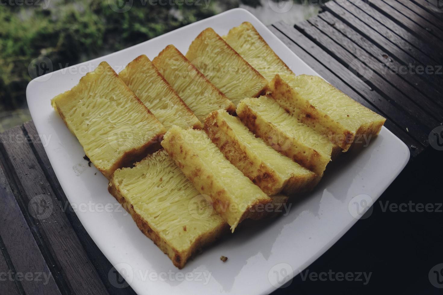 bika ambon, indonesische cake met vierkante plakjes in witte plaat. gele cake uit medan, indonesië. foto