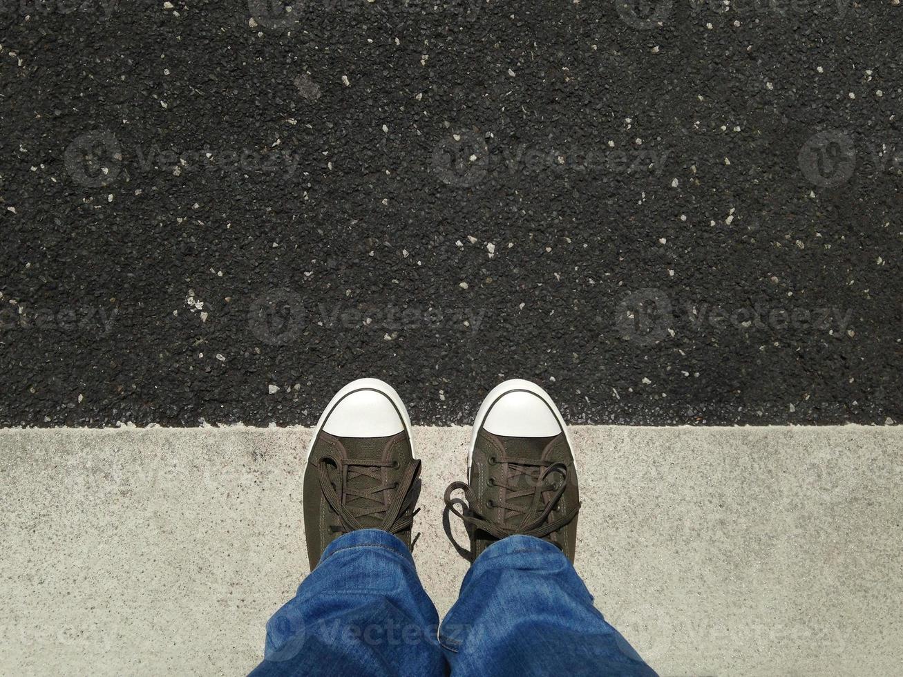 voeten in canvas schoenen die op asfalt staan, uitgelijnd met wegmarkeringen foto