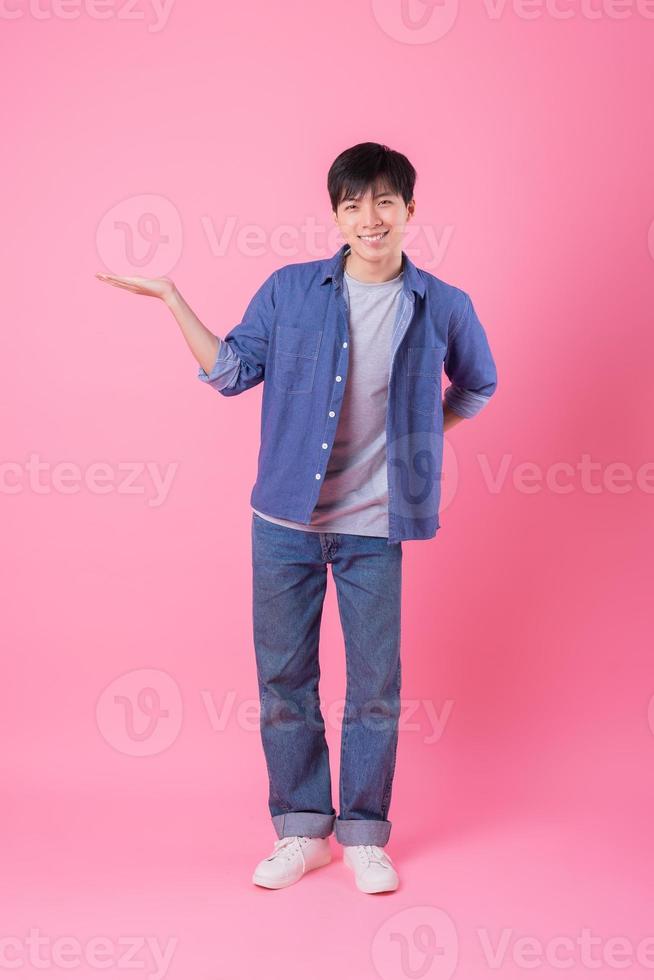 jonge Aziatische man die zich voordeed op roze achtergrond foto