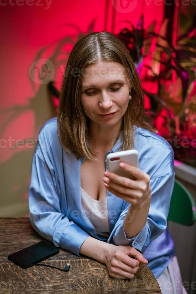 de vrouw zit aan een tafel in een café aan de telefoon en beslist over zakelijke aangelegenheden. foto