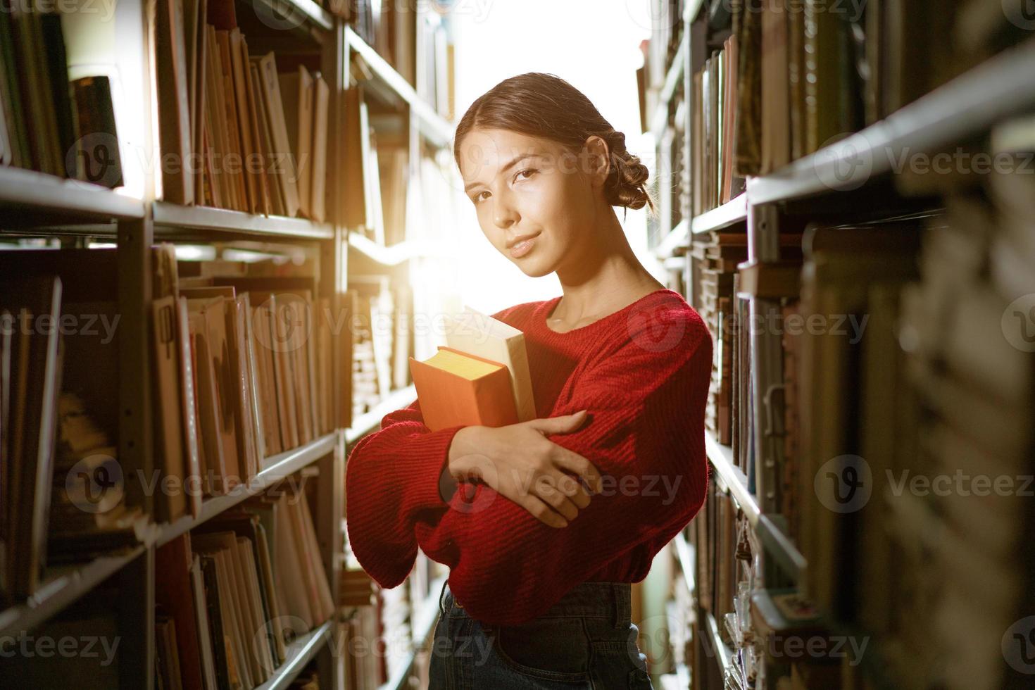 het meisje houdt een boek in haar handen tegen de achtergrond van de bibliotheek. foto