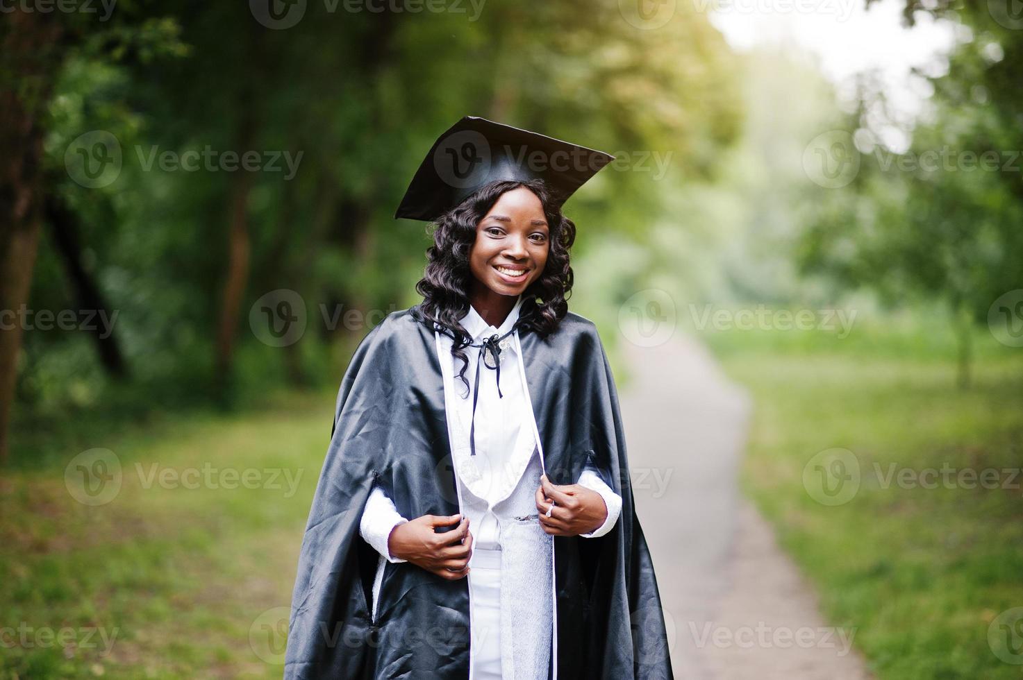 gelukkig mooi zwart Afrikaans Amerikaans meisje met hoed en toga afgestudeerden foto