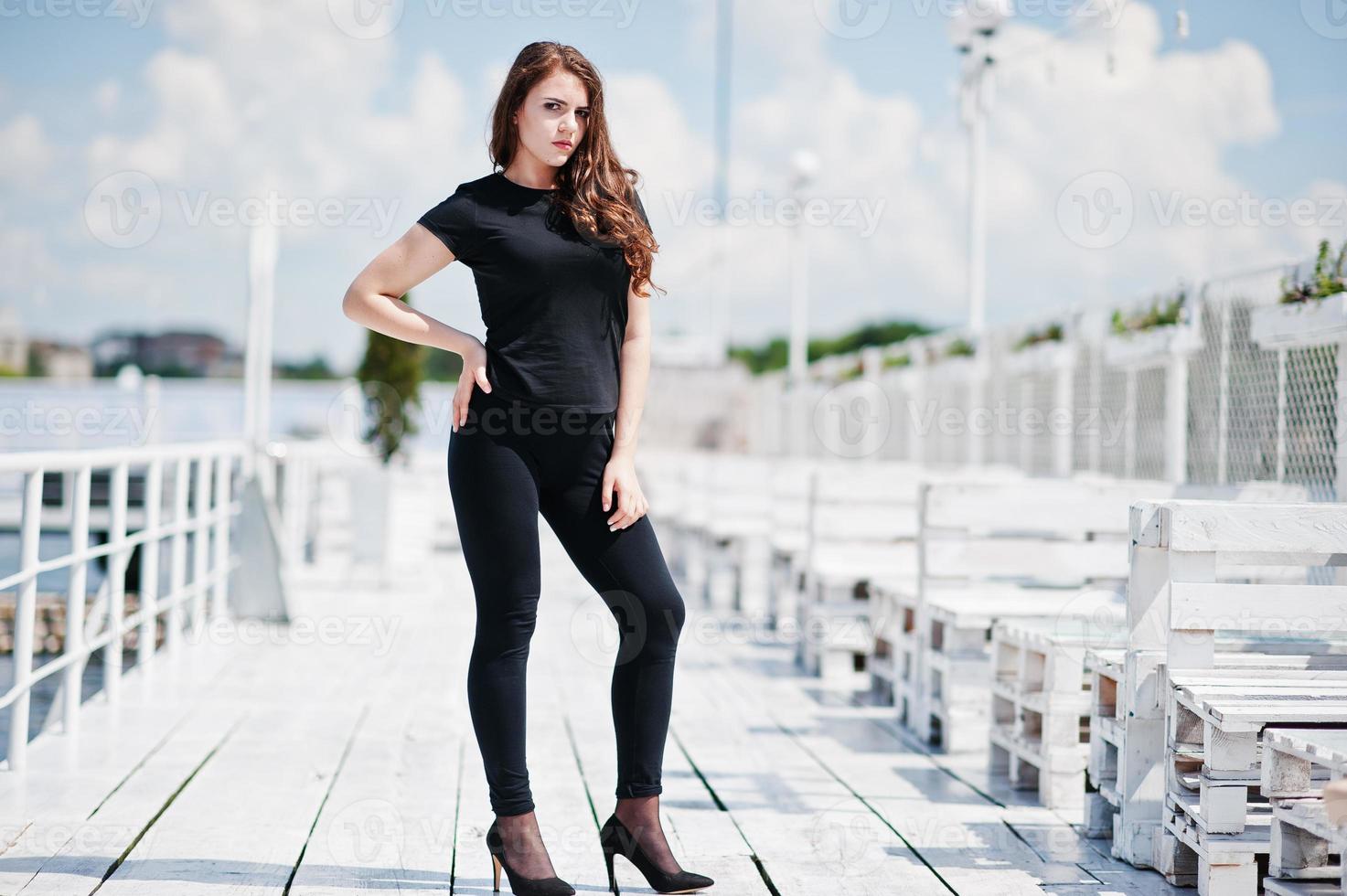 jong meisje met zwarte kleren poseerde op de pier foto