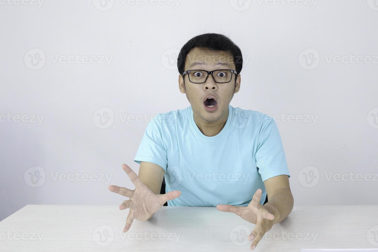 wow en geschokt gezicht van jonge aziatische man met open handgebaar. reclame model concept met blauw shirt. foto