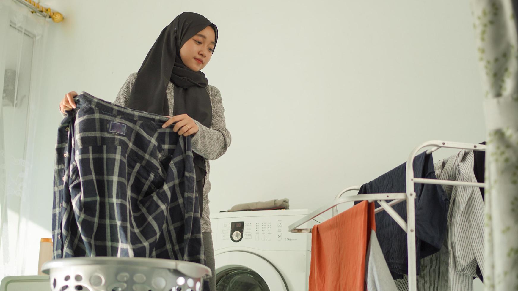 Aziatische vrouw in hijab die haar was thuis droogt foto