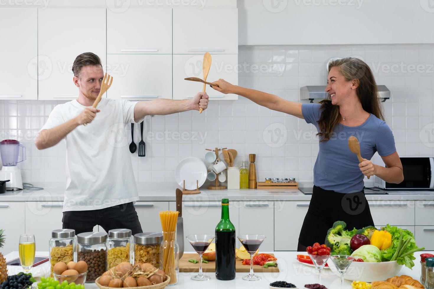 jong koppel samen dansen tijdens het koken van gezond voedsel in de keuken foto