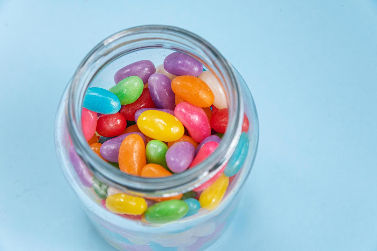 verschillende jelly beans op de blauwe achtergrond in de glazen pot foto