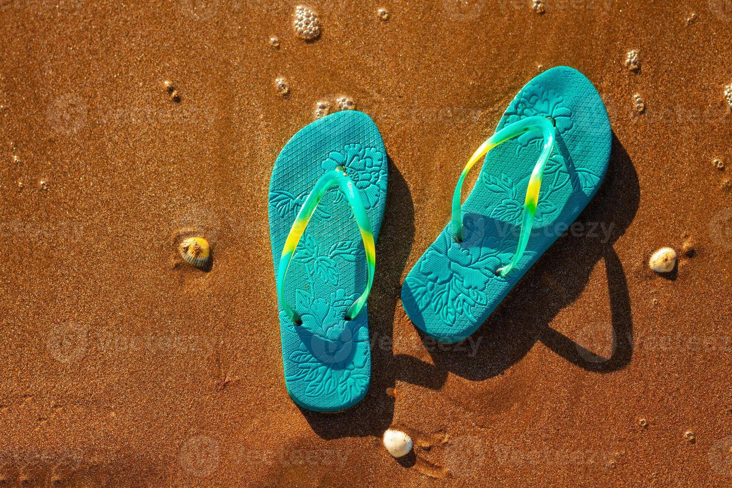 blauwe sandalen op het strand, het concept van rust op de zee foto