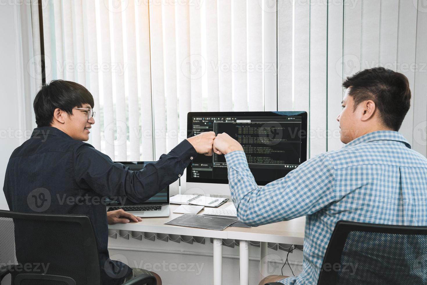 Aziatische softwareontwikkelaars voor werknemers vieren het succesproject met een vuist in de kantoorruimte. foto