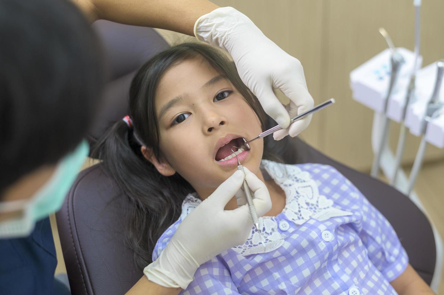 een klein schattig meisje met tanden onderzocht door tandarts in tandheelkundige kliniek, tandencontrole en gezond gebit concept foto