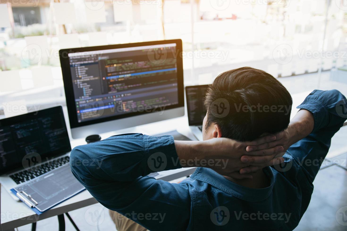 Aziatische programmeurs man zijn ontspannen en kijken naar de code op het computerscherm op kantoor. foto