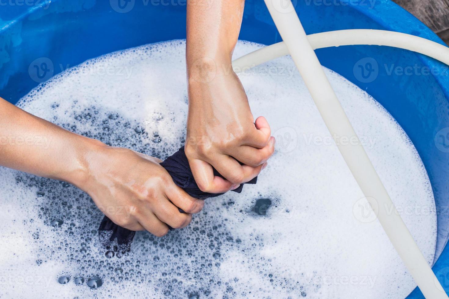 vrouwelijke handen wassen kleding met de hand met wasmiddel in bekken. selectieve focus en ruimte voor tekst. foto