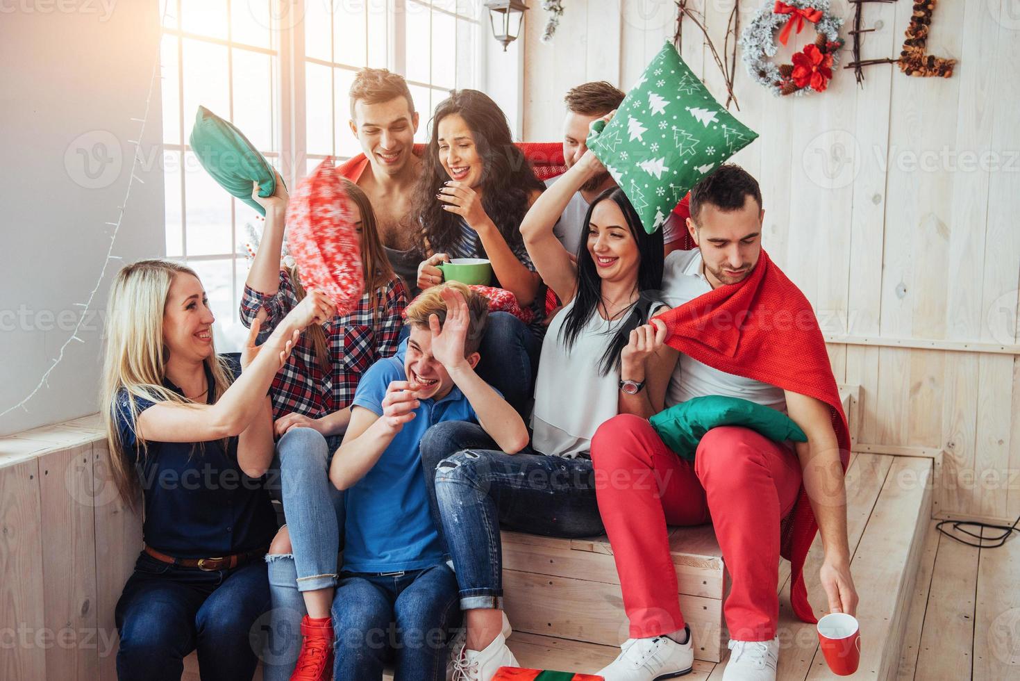 gekke jonge beste vrienden die thuis met kussens vechten. gemengd ras groep mensen. conceptentertainment en lifestyle foto