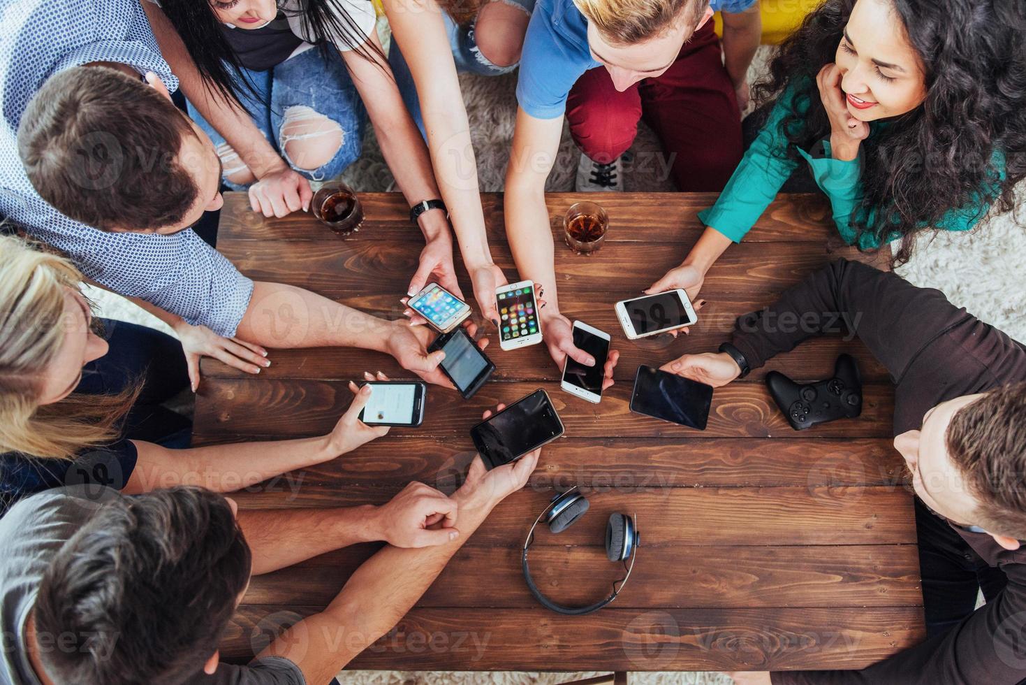 bovenaanzicht handen cirkel met behulp van telefoon in café - multiraciale vrienden mobiel verslaafd interieur scène van bovenaf - wifi verbonden mensen in bartafel vergadering - concept van teamwork foto