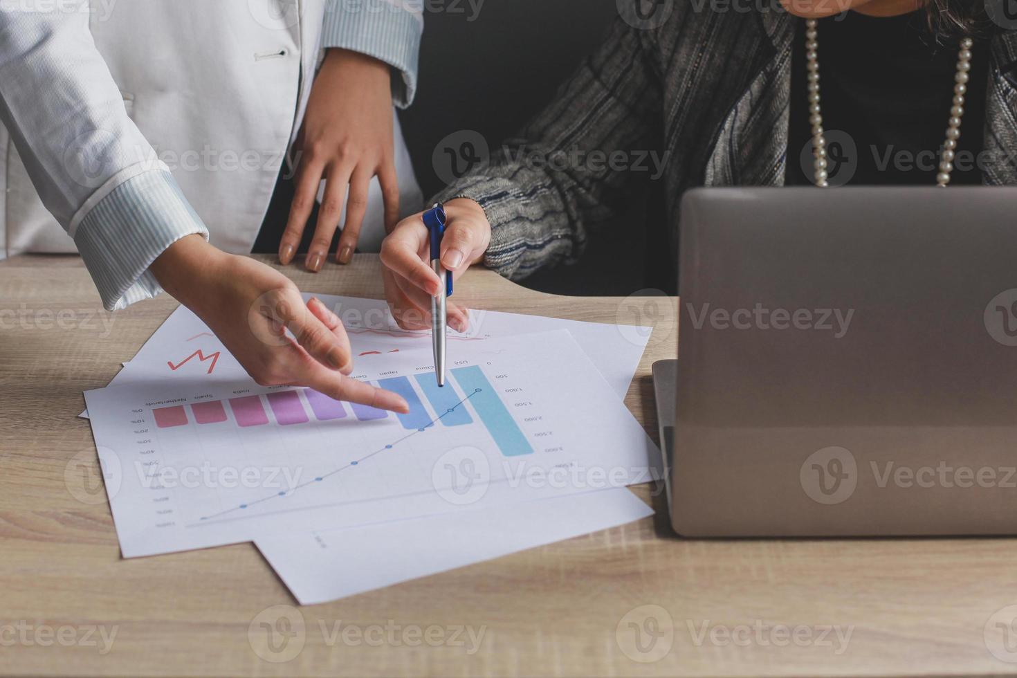 bijgesneden opname van twee vrouwelijke werknemers die discussiëren door met haar wijsvinger naar het kaartblad op het bureau te wijzen foto