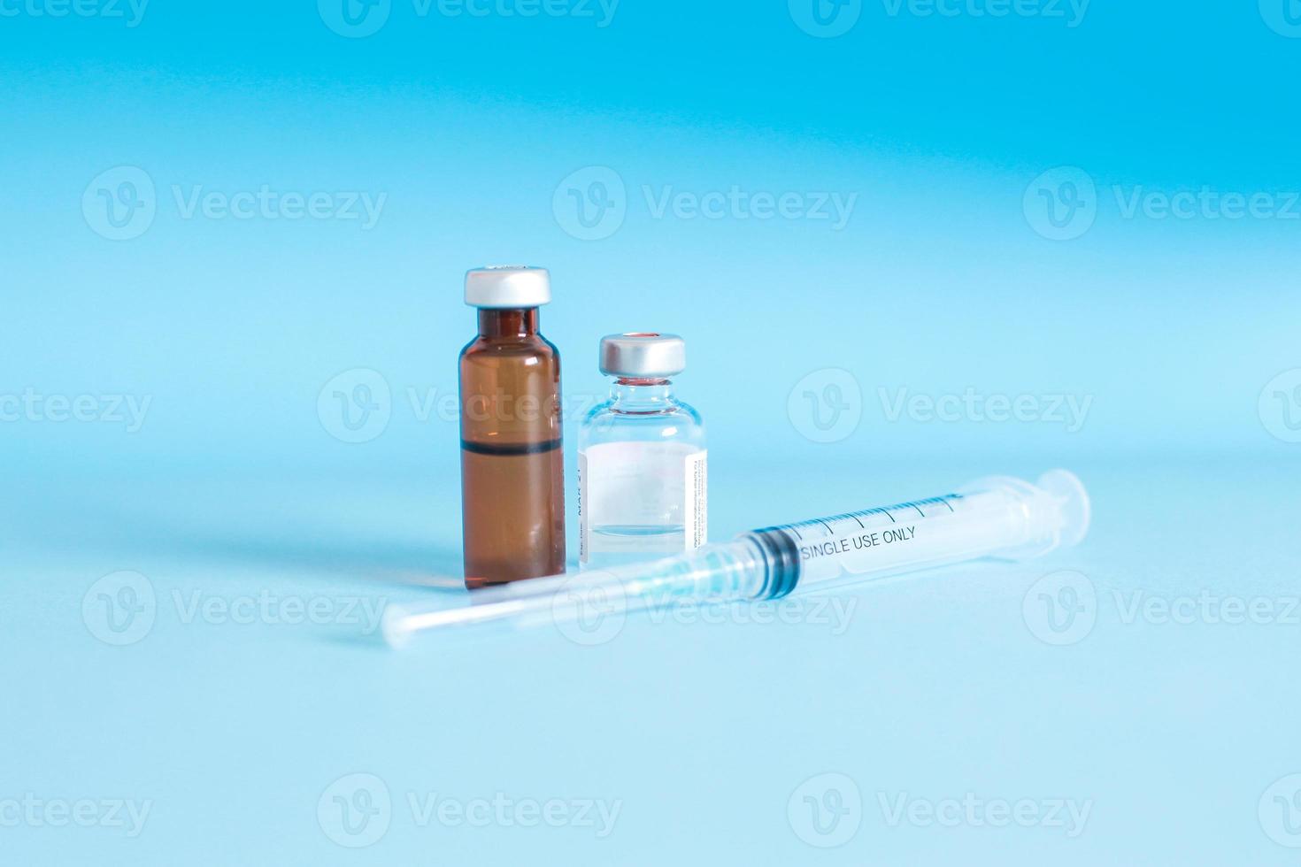 vaccin fles en medische spuit met injectienaald geïsoleerd op blauwe achtergrond. geneeskunde, vaccinatie, immunisatie en gezondheidszorg concept foto