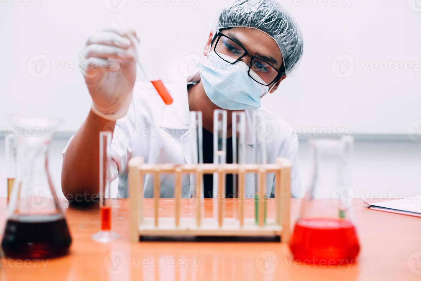 jonge aziatische wetenschapper of onderzoeker kijkt naar de reageerbuis of het monster in het laboratorium. nationale wetenschapsdag, wereldwetenschapsdag foto