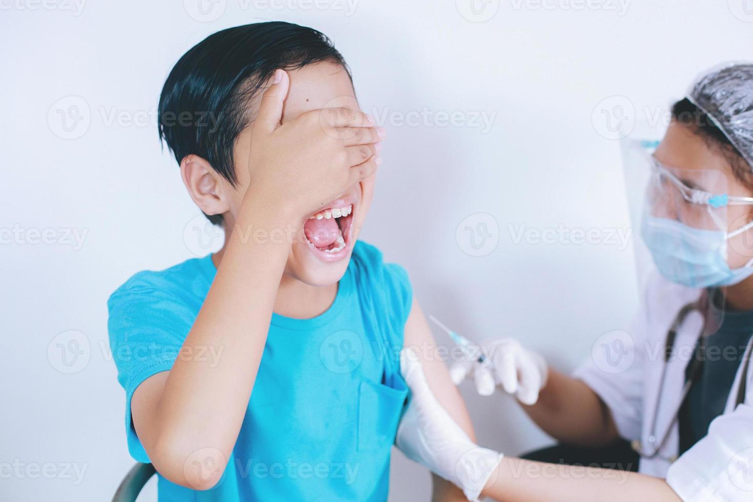 jongen schreeuwt vanwege pijn bij vaccininjectie, injectiefobie. geneeskunde, vaccinatie, immunisatie en gezondheidszorg concept foto