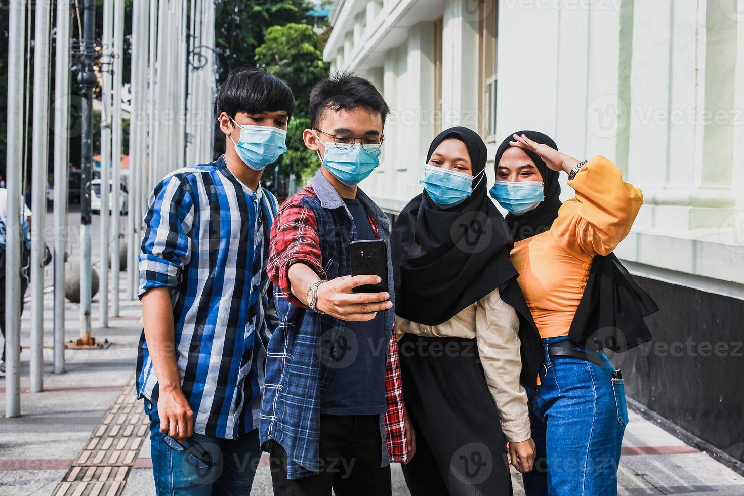 vrienden met beschermend veiligheidsmasker die plezier hebben met het nemen van selfies tijdens de pandemie van het coronavirus in de zomer. foto