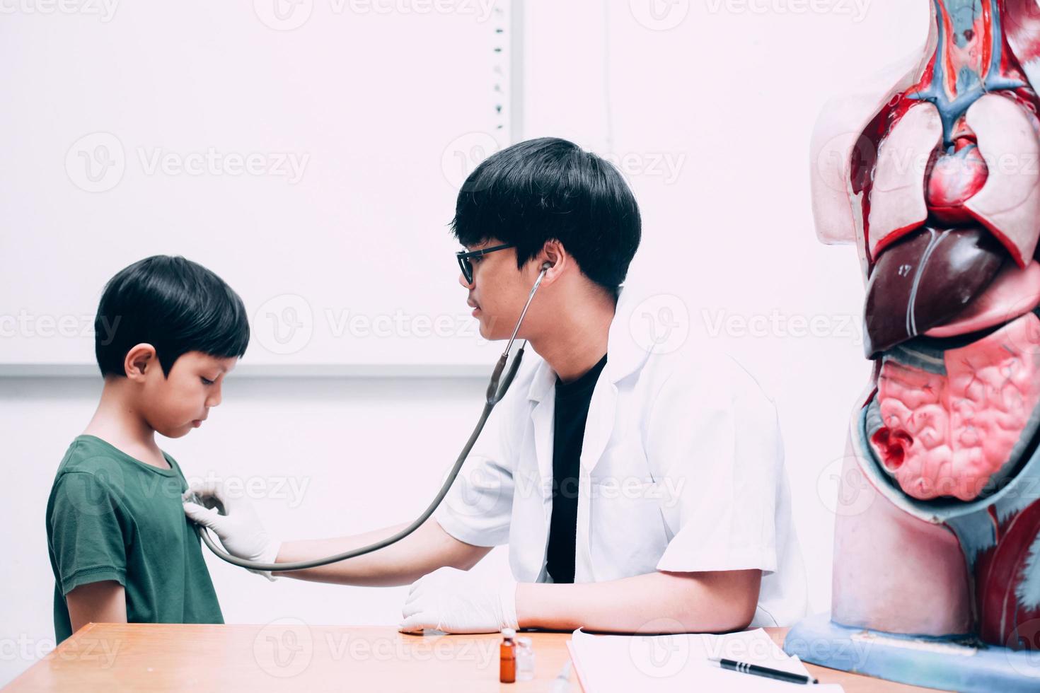 mannelijke arts houdt stethoscoop vast die kind jongen patiënt onderzoekt foto