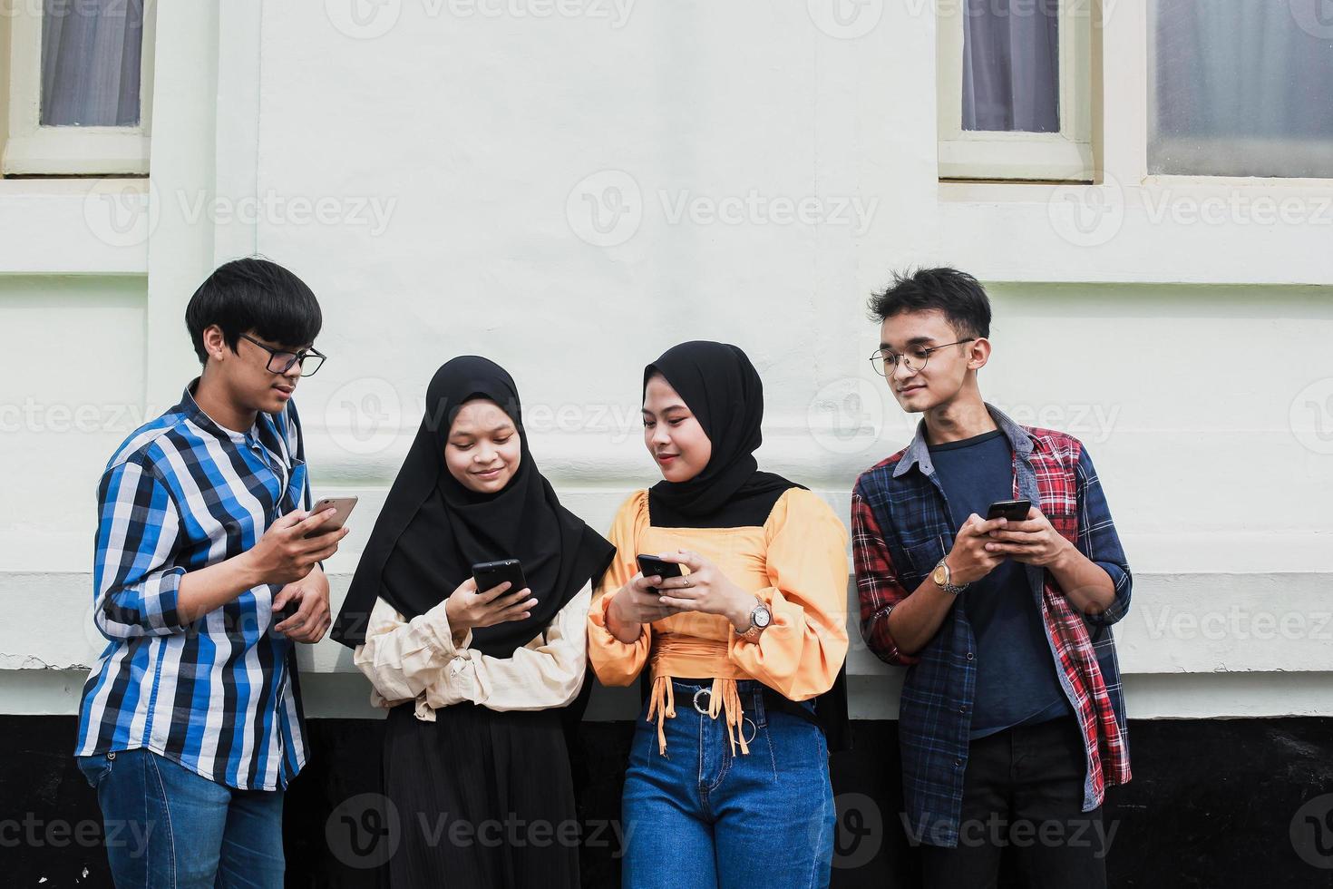 gelukkige duizendjarige vrienden die smartphones gebruiken - jonge studenten die plezier hebben in de buitenlucht - vriendschap en stadslevensstijlconcept foto