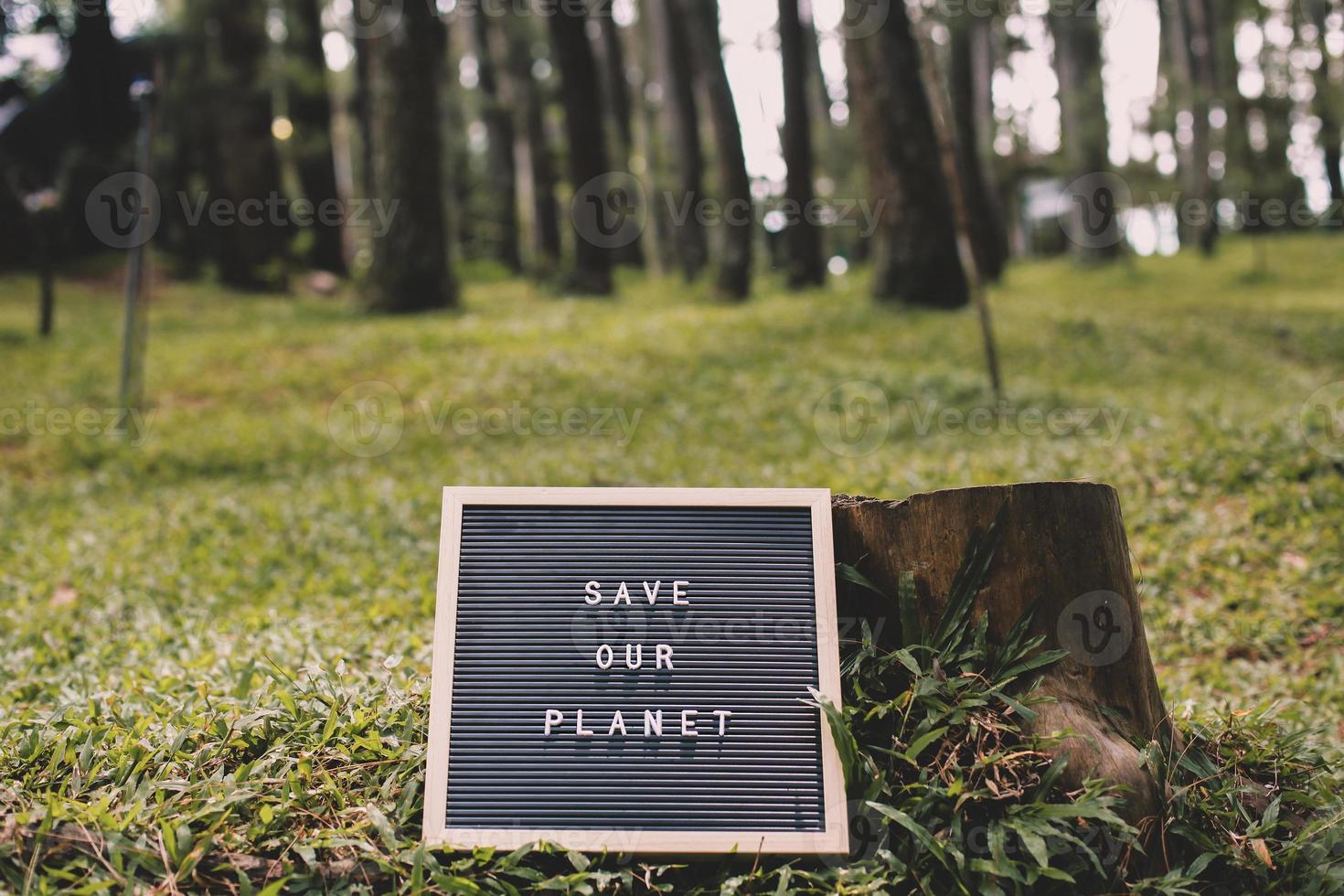 gekapte boom en citaat op letterbord zegt red onze planeet liggend op het groene gras van het bos foto