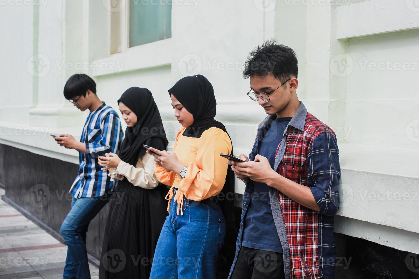 groep vrienden kijken naar slimme mobiele telefoons - tieners verslaving aan nieuwe technologische trends - concept van jeugd, technologie, sociaal en vriendschap foto