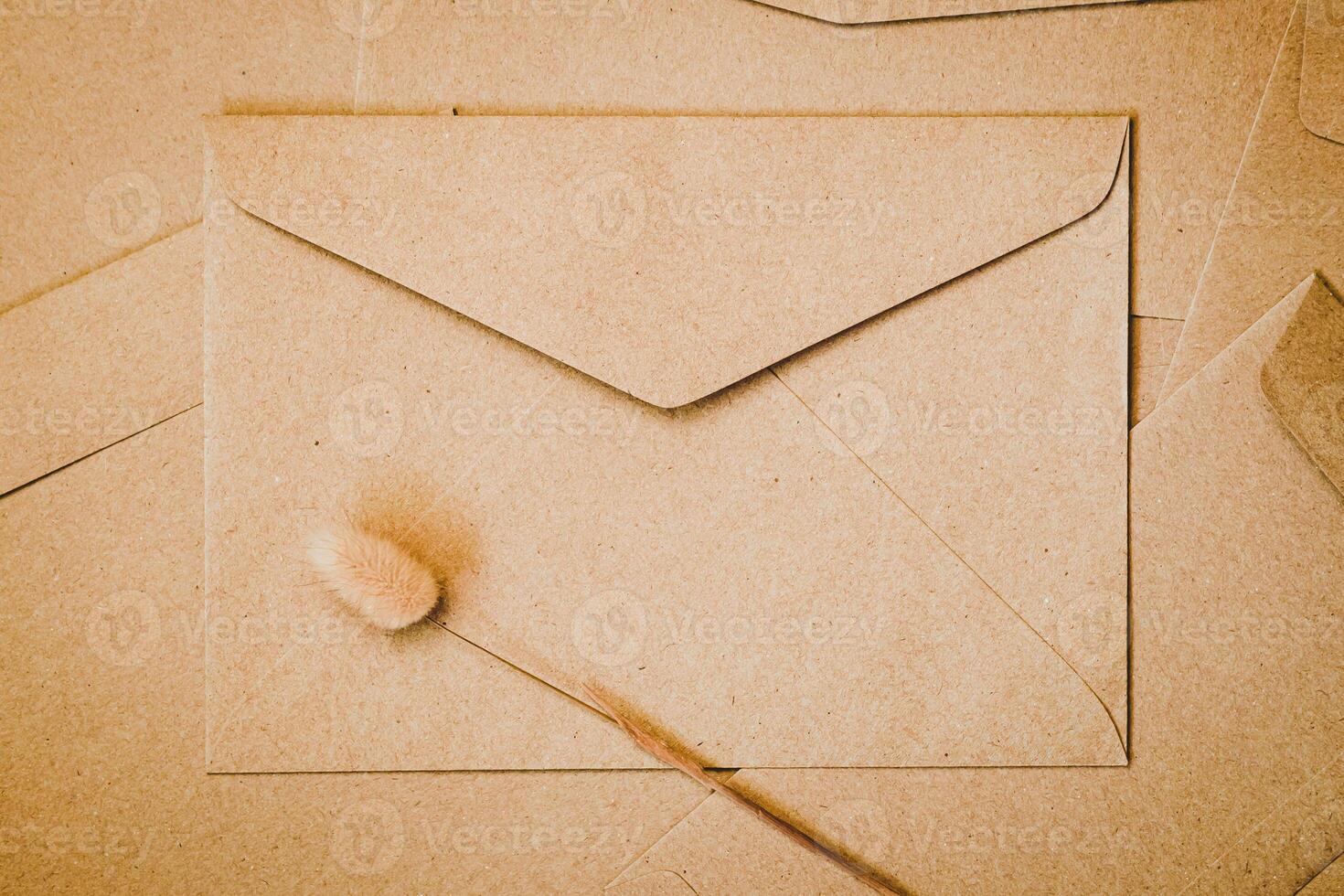 bruine papieren envelop met konijnenstaart droge bloem. close-up van ambachtelijke envelop. plat lag minimalisme. foto