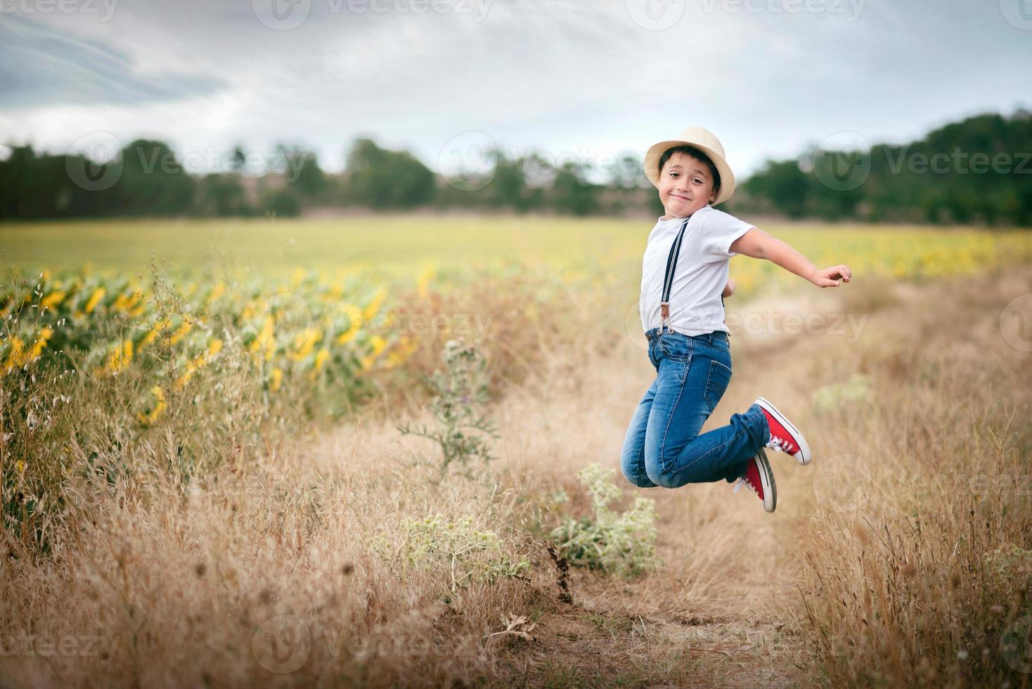 lachende jongen die in het veld springt foto