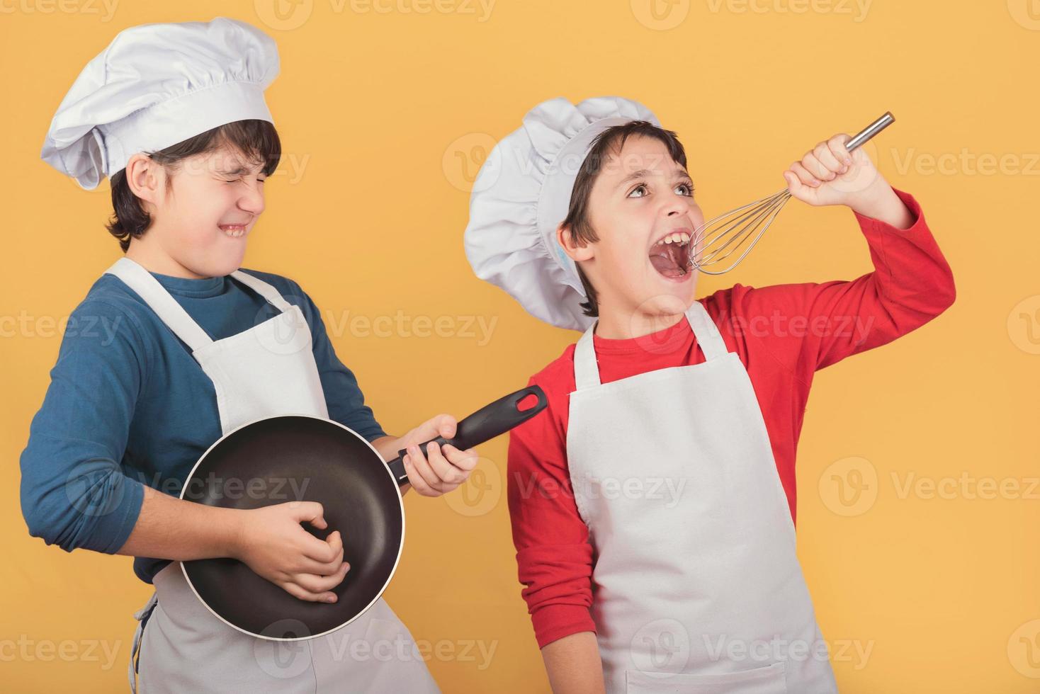 grappige jongens die zingen met een koksmuts die de garde en pan vasthoudt foto