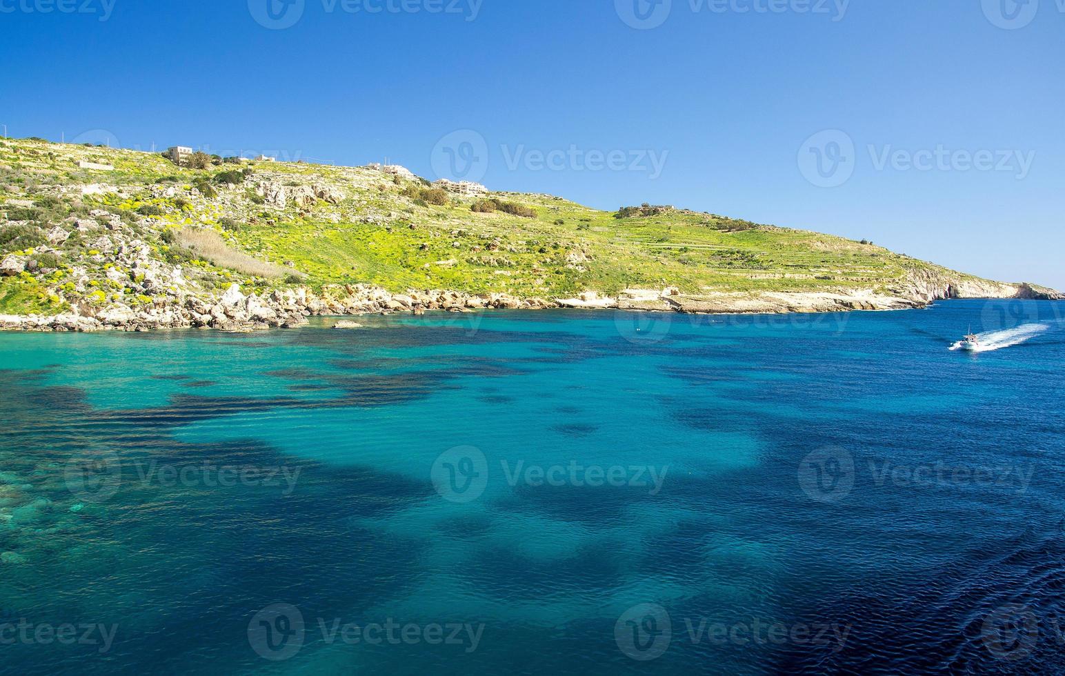 blauwe water en zeilmotorboot in de buurt van de stad mgarr, gozo-eiland, malta foto