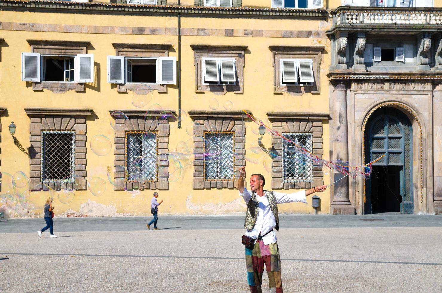 Lucca, Italië man blaast kleurrijke zeepbellen en speelt met kleine jonge kinderen foto