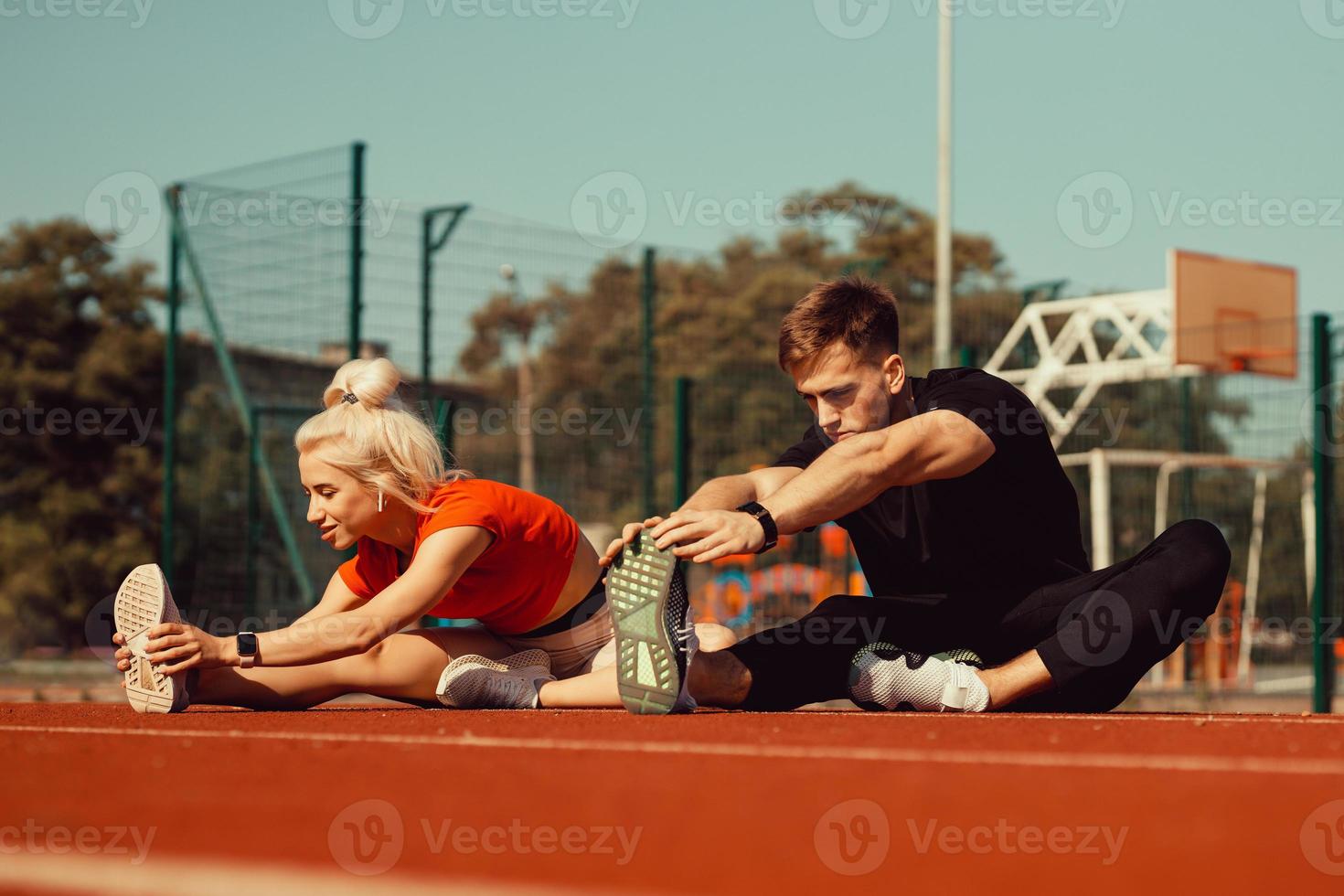 meisje en een jongen doen een warming-up voor sportoefeningen in het schoolstadion foto