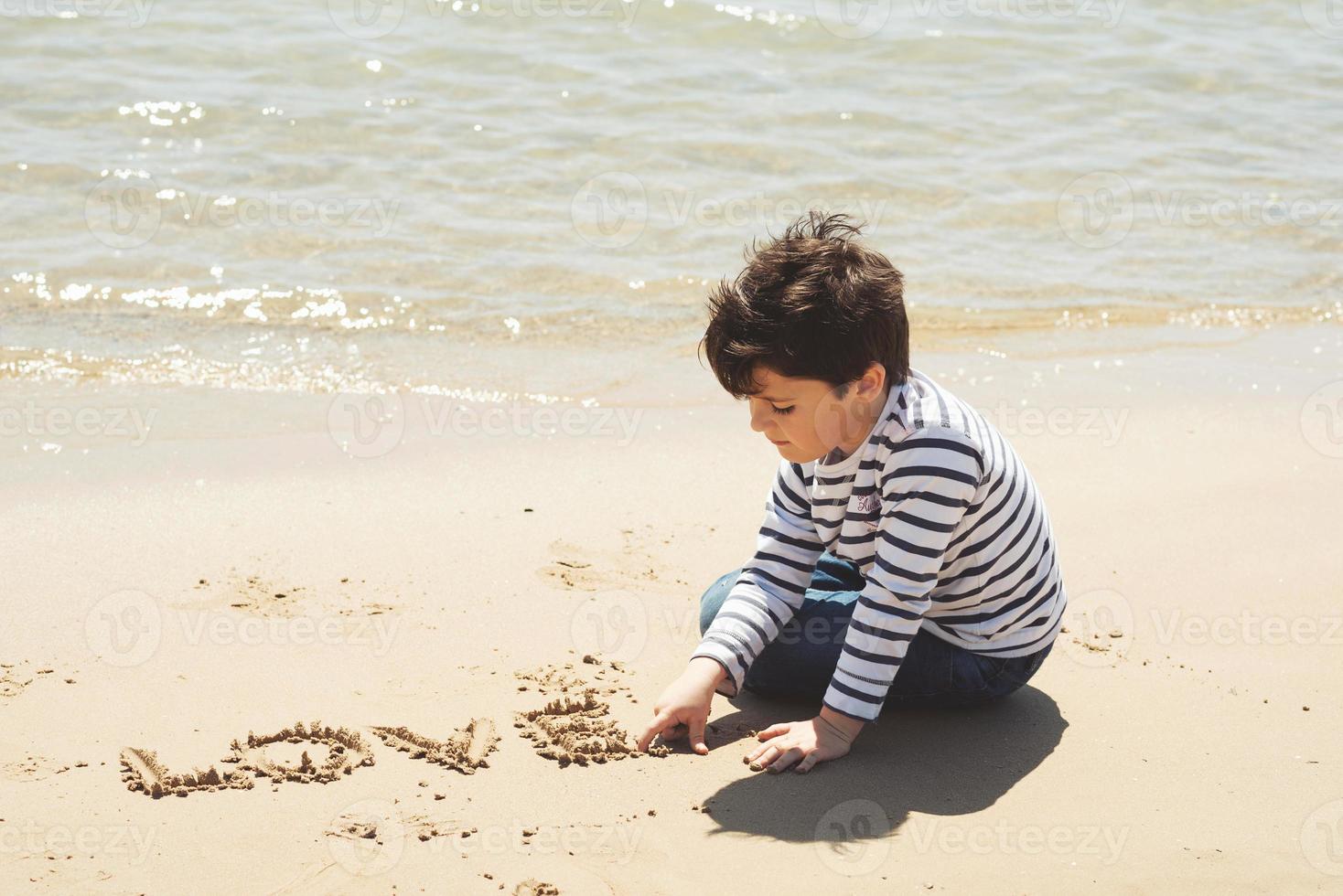 verdrietig jongetje zittend op het strand foto