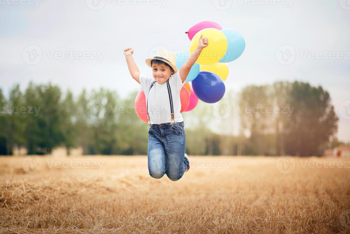 jongen die met ballonnen in het veld springt foto