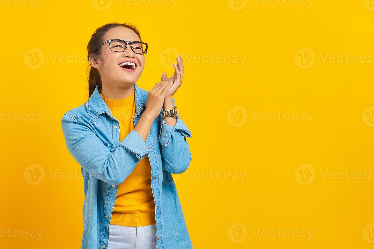 portret van lachende jonge Aziatische studente in denim kleding voelt zich vrolijk heeft witte tanden, kijkend naar camera met vertrouwen geïsoleerd op gele achtergrond. mensen oprechte emoties levensstijl concept foto