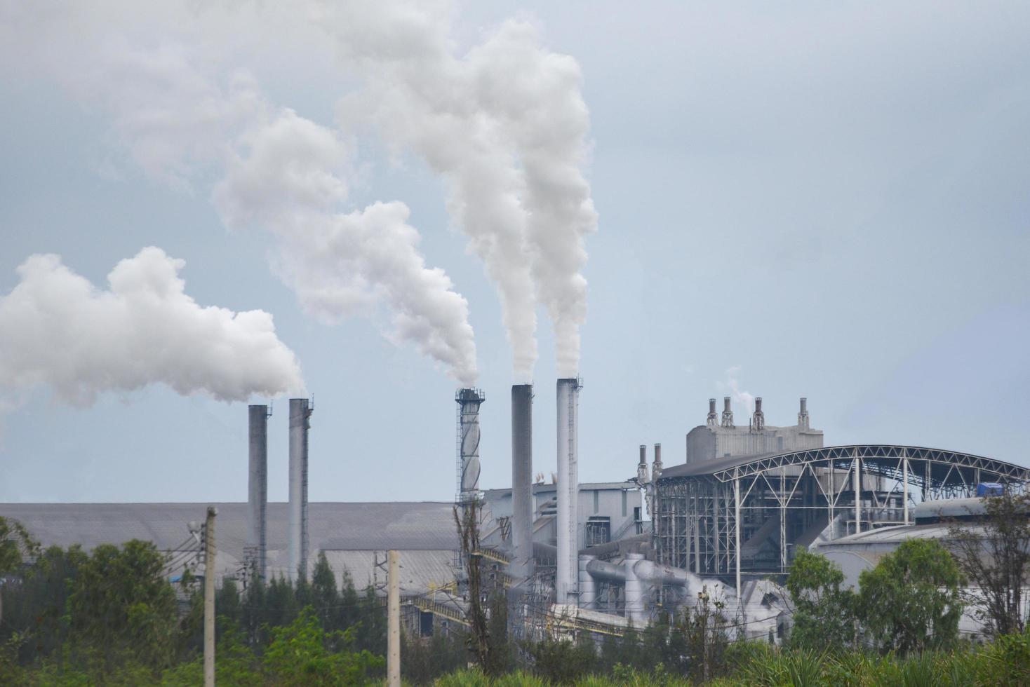 witte rook komt uit schoorstenen of uitlaatpijpen in de fabrieksschoorstenen stoten waterdamp uit die condenseert tot een witachtige wolk voordat deze verdampt, stoomsuikerfabriek, elektriciteitsopwekking foto