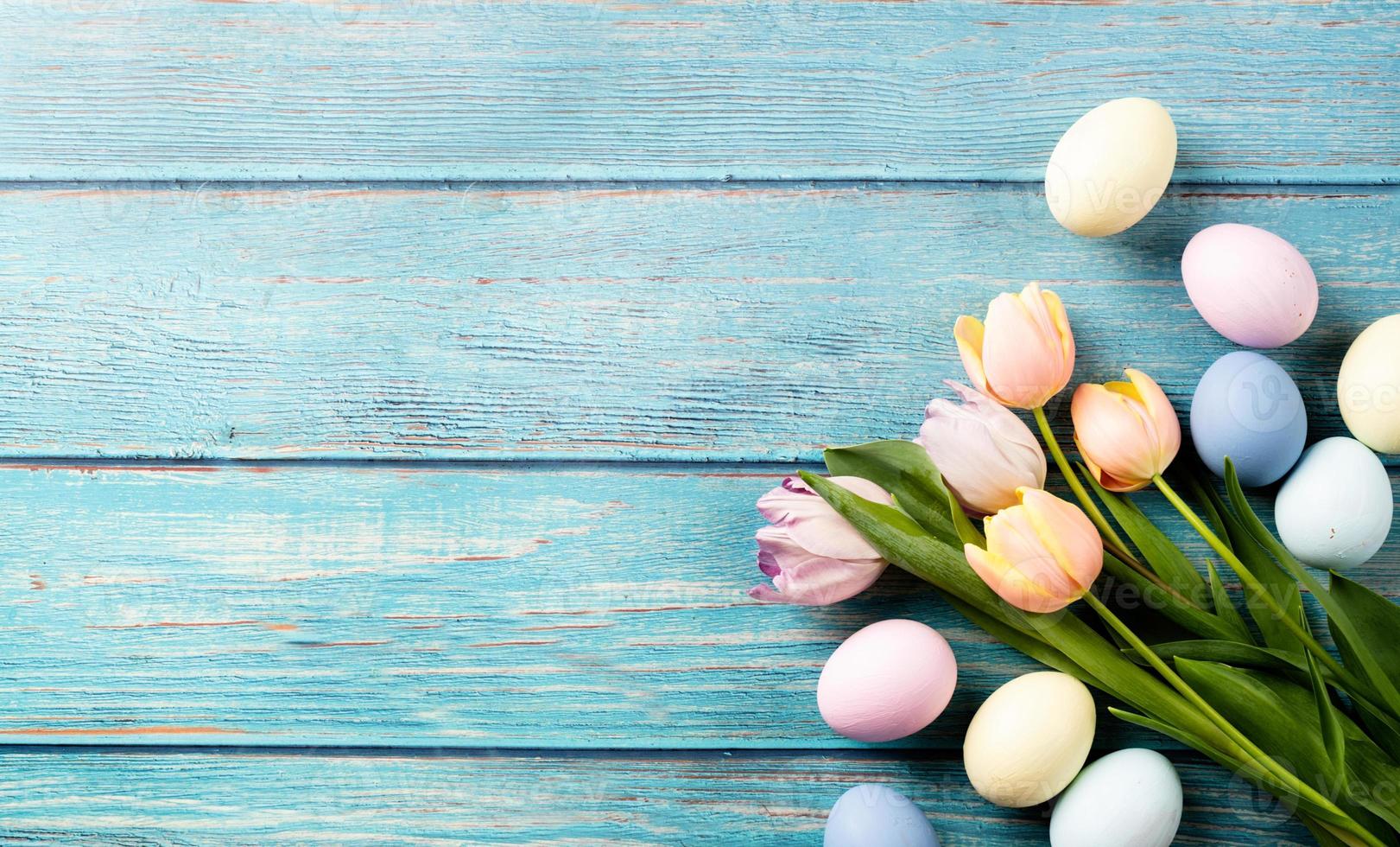 Pasen achtergrond met eieren en tulpen op blauwe houten achtergrond, bovenaanzicht plat lag foto
