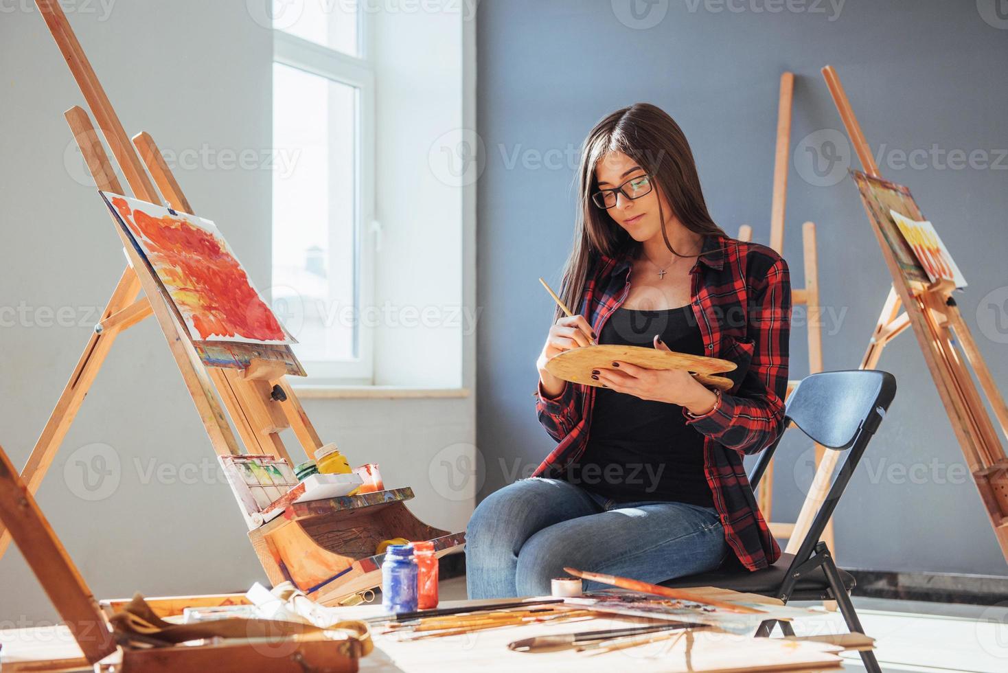 donkerharige kunstenaar met een penseel in zijn hand en tekent een afbeelding op canvas. denkt dat tekenen op foto