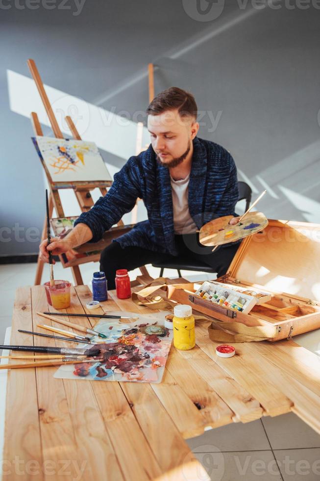 ontworpen door kunstenaar man afwerking van zijn meesterwerk houdt een borstel in de hand. foto