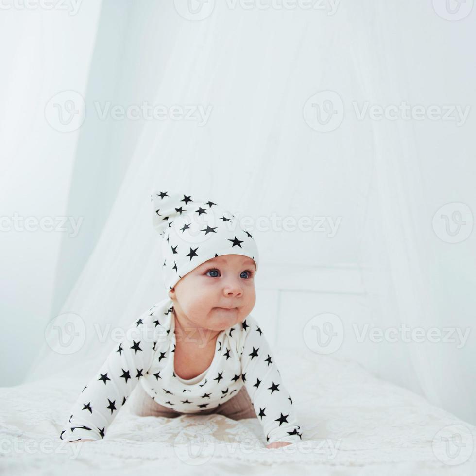 pasgeboren baby gekleed in een wit pak en zwarte sterren is een wit zacht bed in de studio foto
