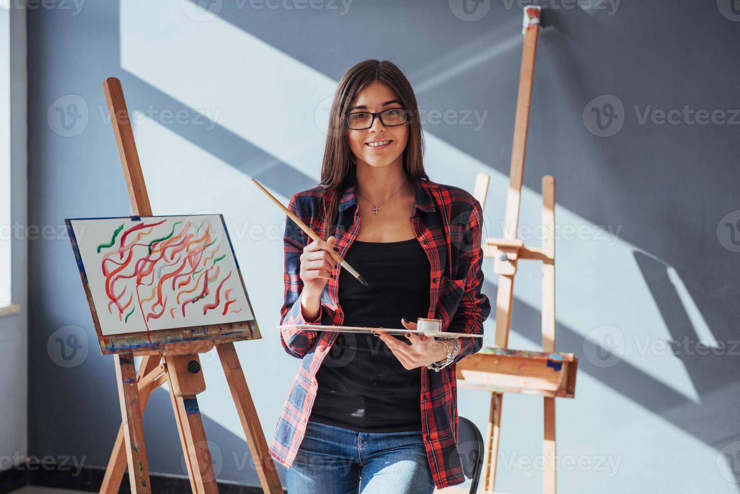 donkerharige kunstenaar met een penseel in zijn hand en tekent een afbeelding op canvas. denkt dat tekenen op foto