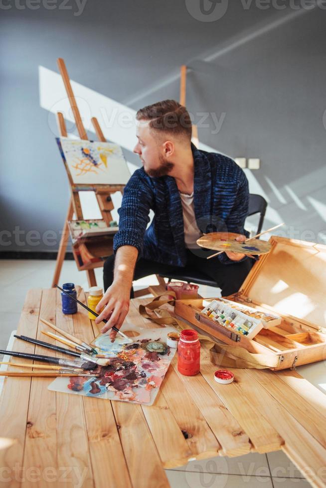 ontworpen door kunstenaar man afwerking van zijn meesterwerk houdt een borstel in de hand. foto